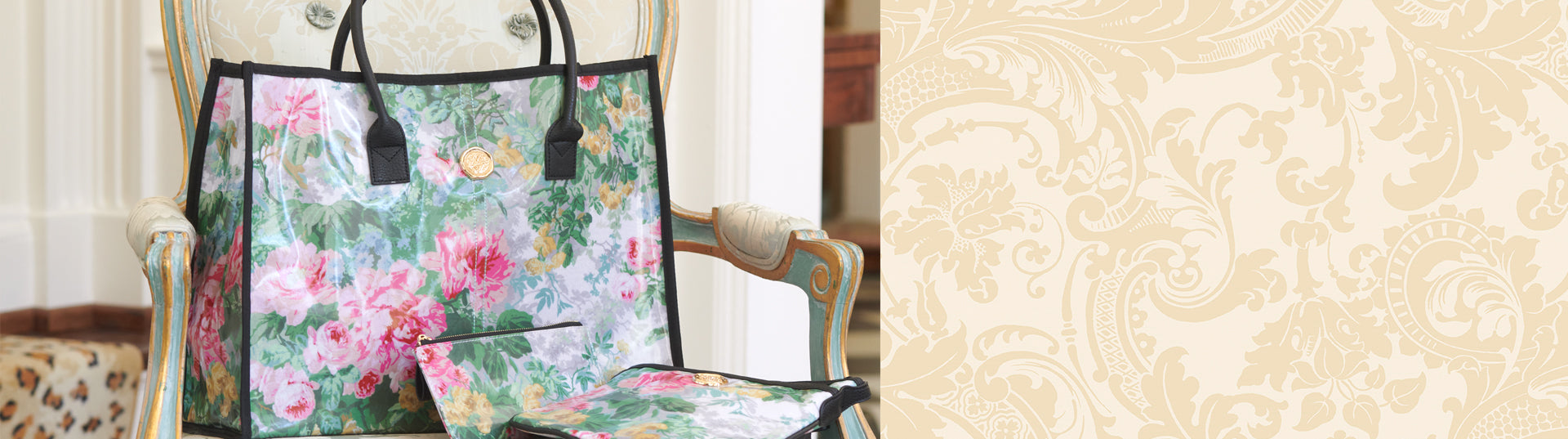 A floral-patterned handbag with black handles and a matching small pouch rests on an ornate armchair.