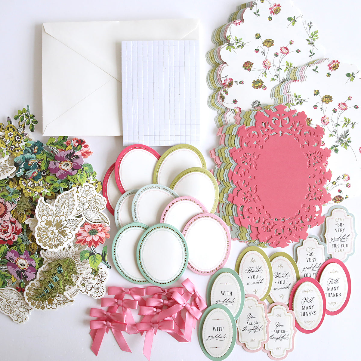 An assortment of Simply Thankful Easel Card Making Kits including floral cut-outs, decorative labels, ribbon bows, and handmade cards on a white surface.