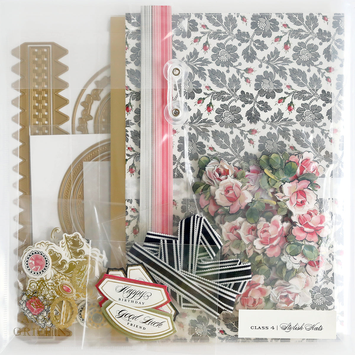 A crafting kit featuring floral-patterned paper, metal dies, ribbons, and various decorative embellishments.