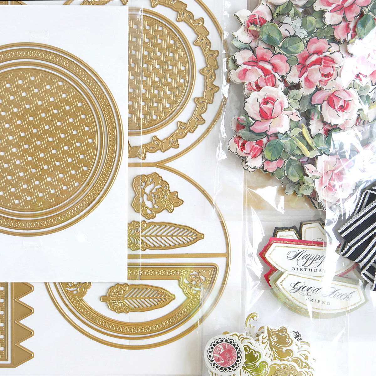 Assorted decorative craft supplies, including gold die-cut shapes and floral paper embellishments, arranged on a white surface.
