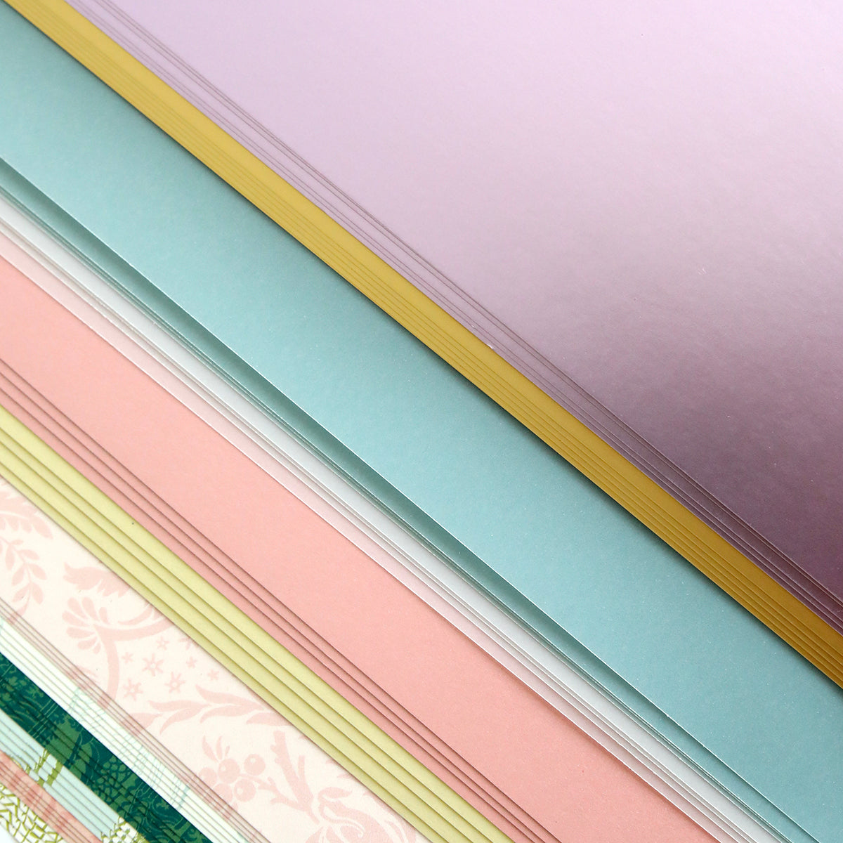 The Crop at Home 5 Swag Materials feature stacks of pastel-colored and patterned premium papers arranged in overlapping layers—perfect for your next crafting project.