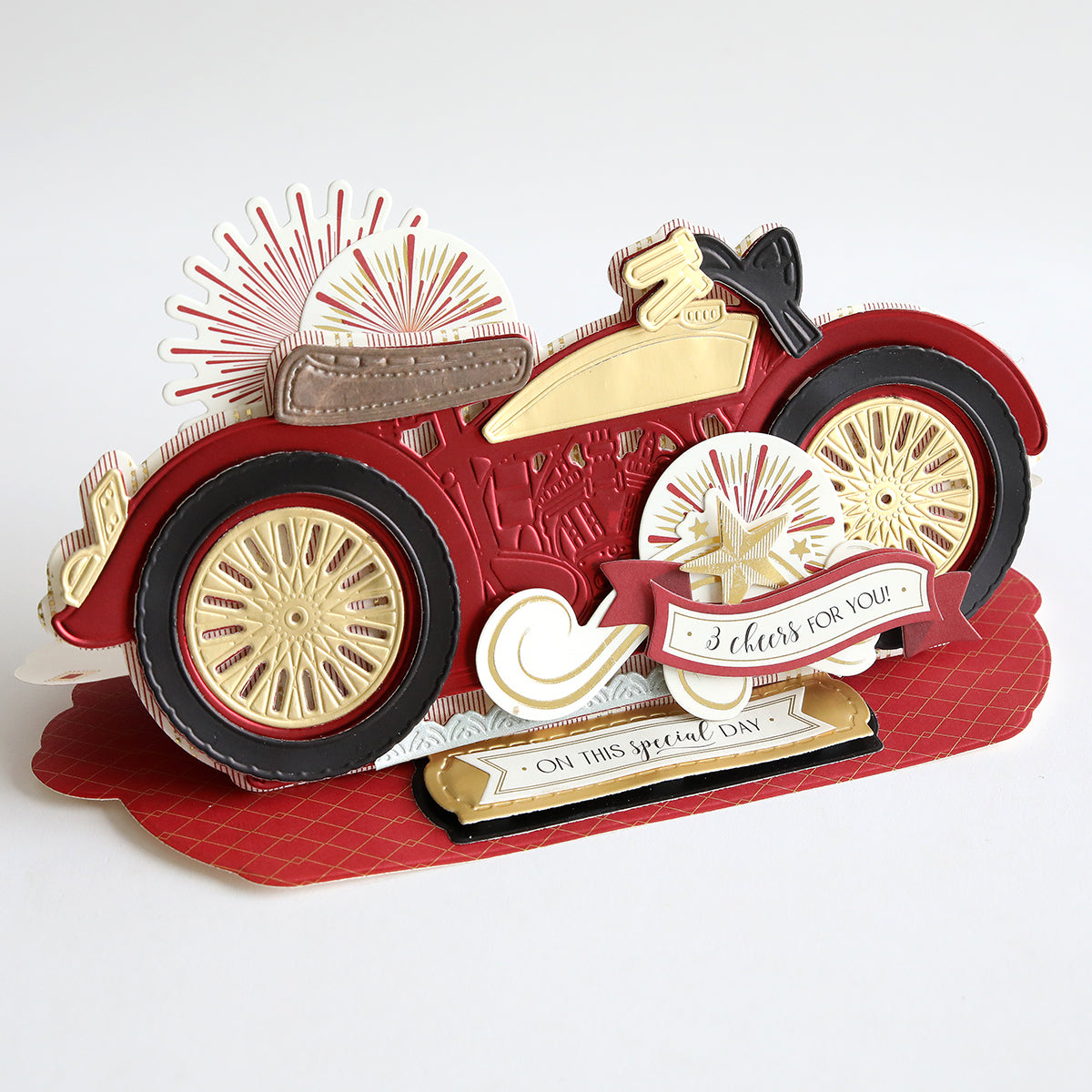 A pop-up card designed with the Vintage Motorbike Slimline Easel Dies, showcasing a red and gold vintage motorcycle motif adorned with decorative features and text that reads "3 cheers for you!" and "On this special day.