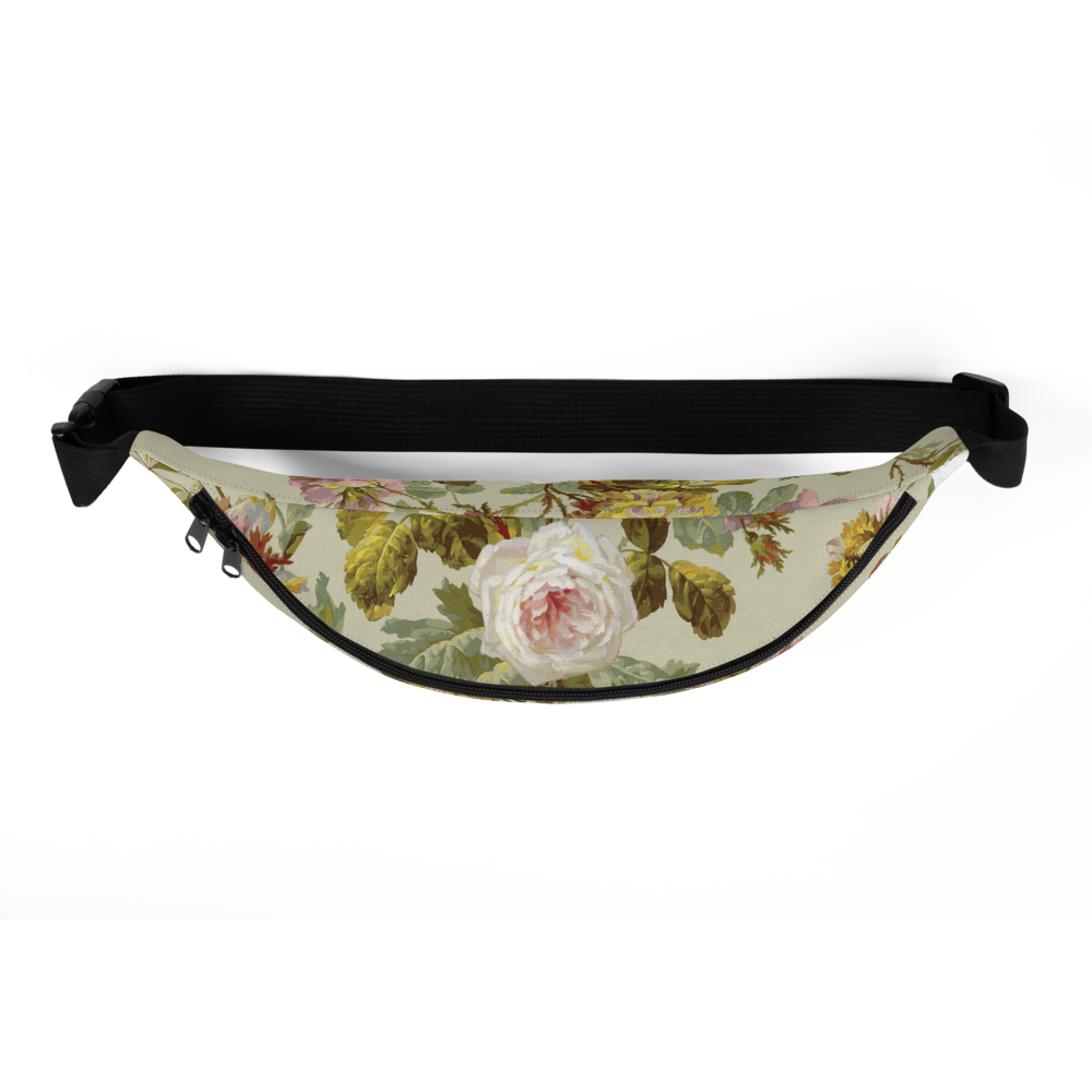 The Fanny Pack features a large white rose with lush green leaves on a beige background, complemented by adjustable black straps against a plain black backdrop.