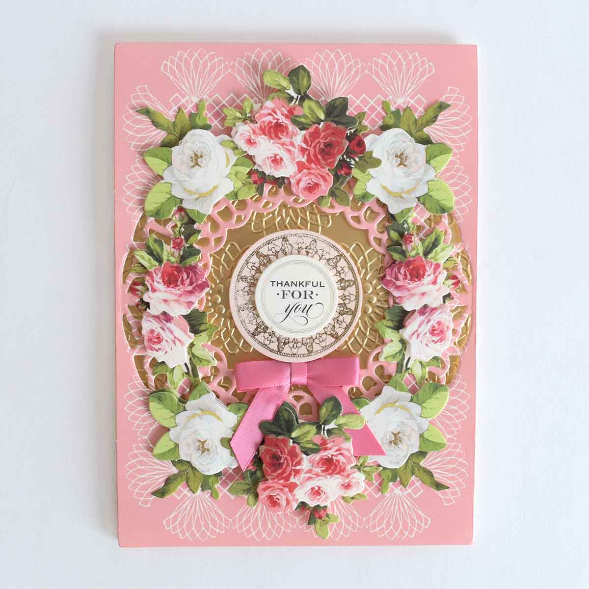 a card with a pink ribbon and flowers on it.