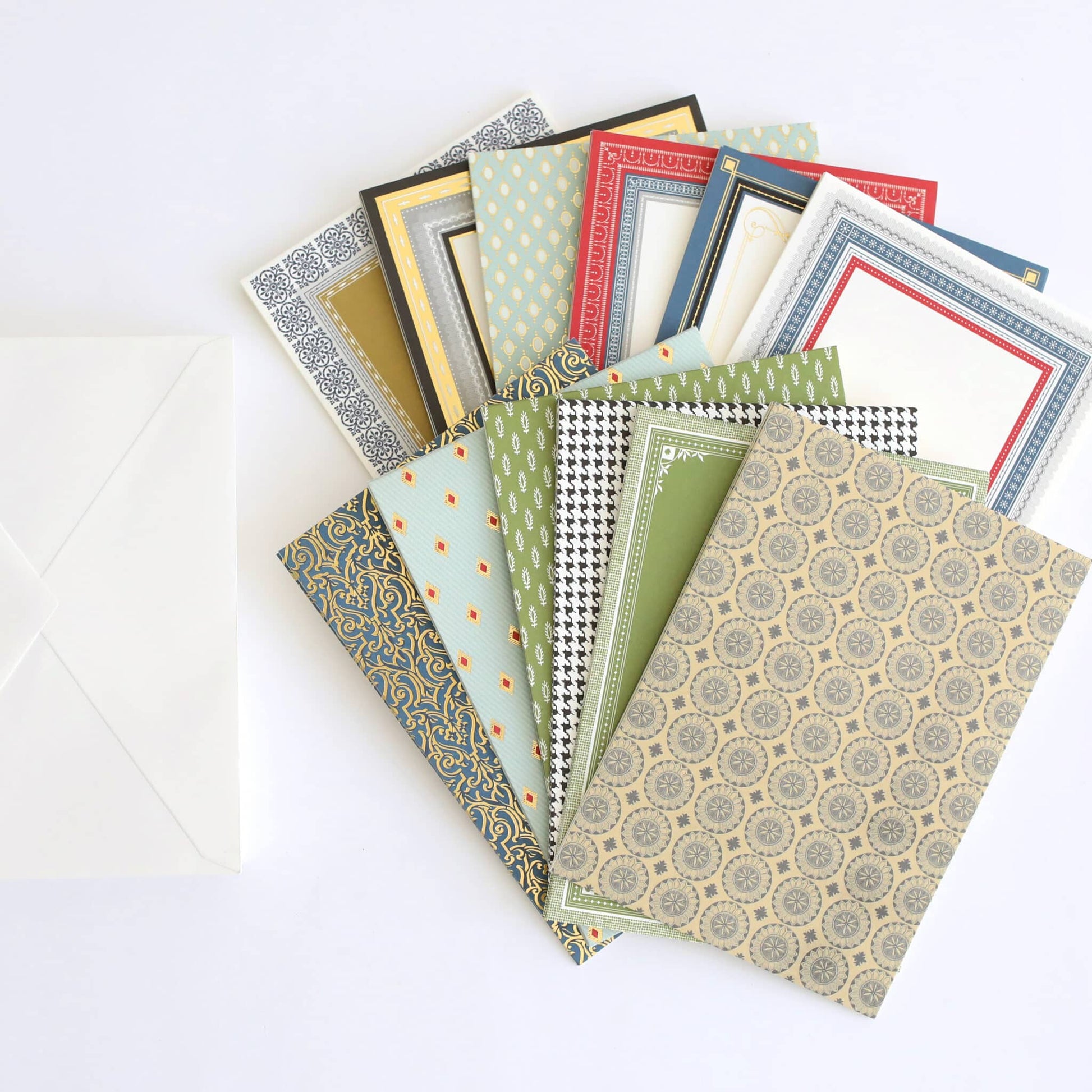 a pile of different colored papers next to a white envelope.