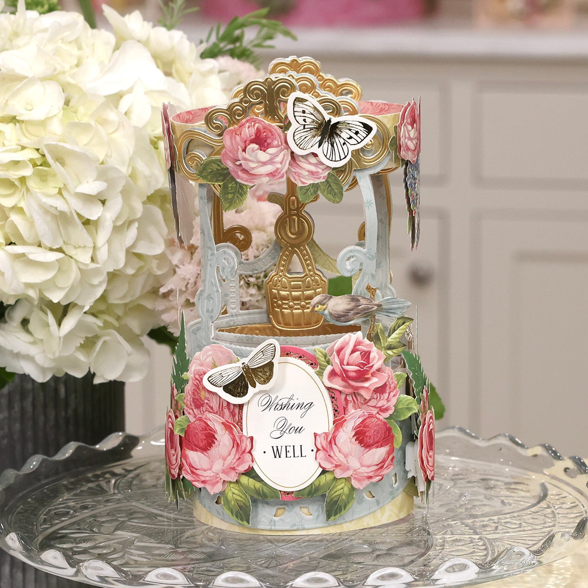 A Wishing Well Easel Finishing School Class with flowers and butterflies on a table.