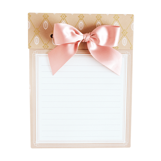 a notepad with a pink bow on top of it.
