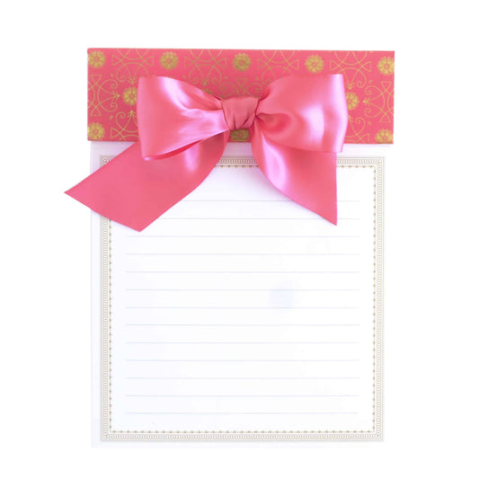 a notepad with a pink bow on top of it.