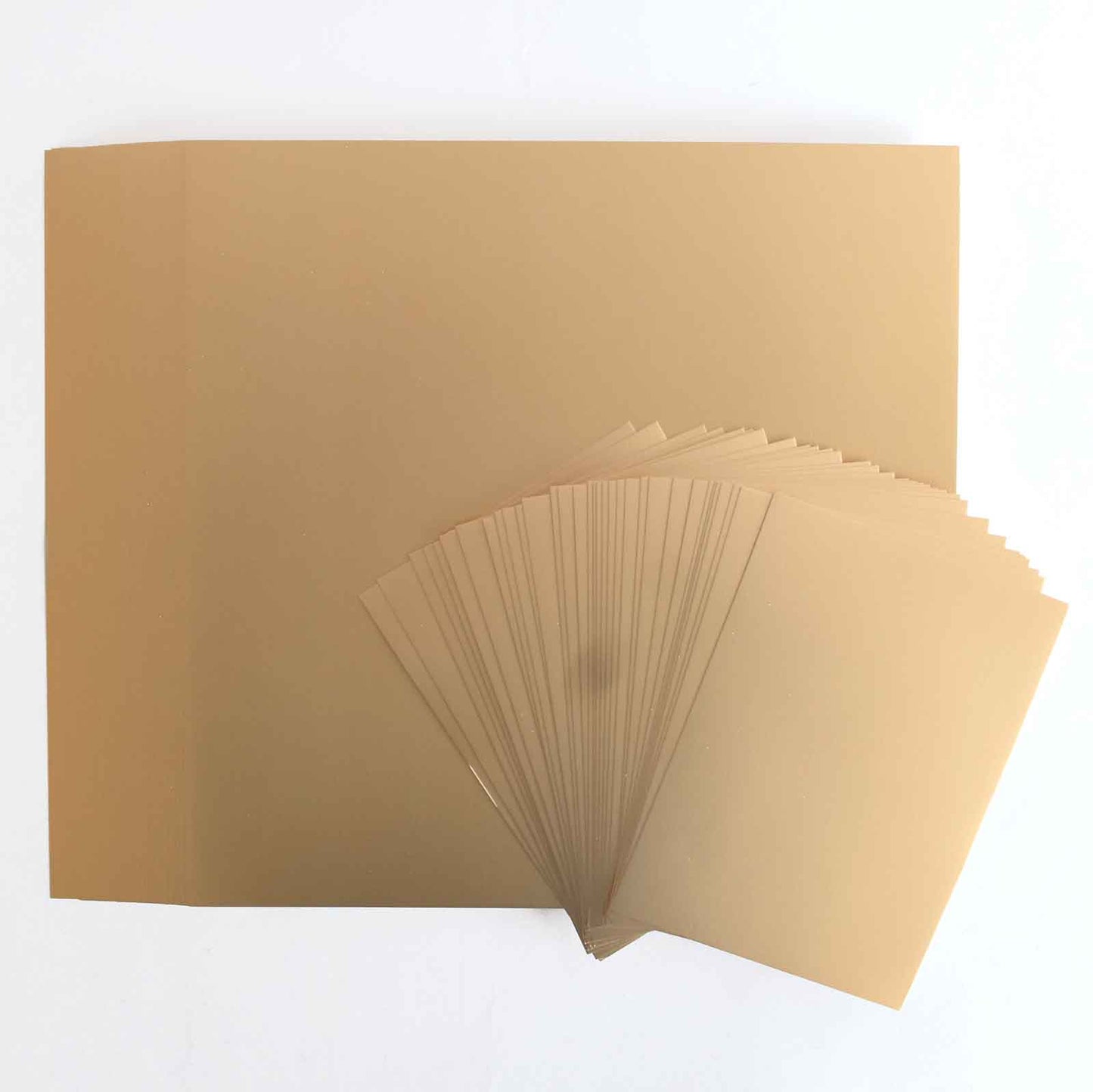 A stack of brown paper sheets is spread on a surface, with some Rose Gold Foil Matte Cardstock sheets fanned out in the foreground.