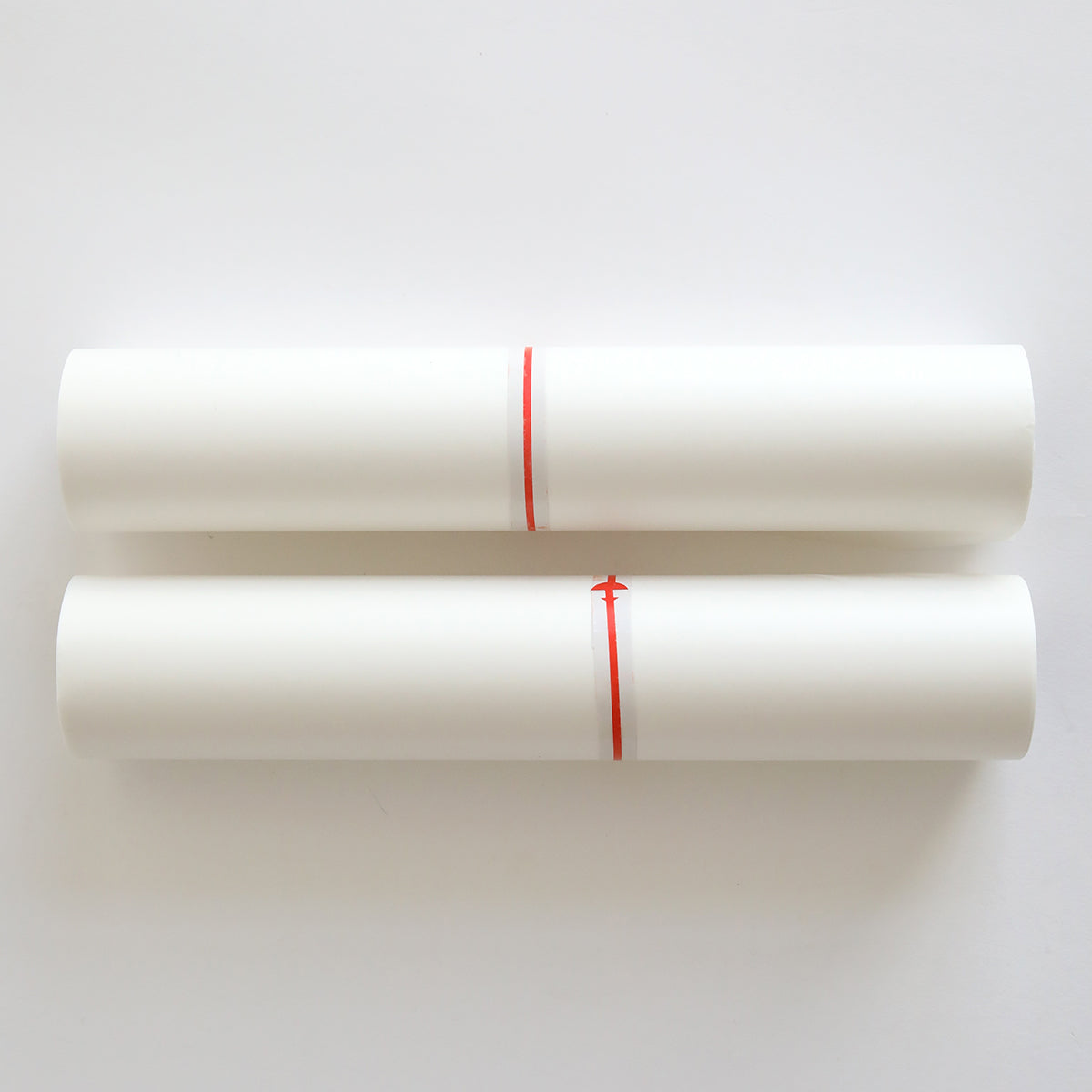 two white rolls of paper tied with red string.