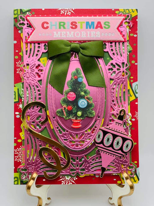 A christmas card with a pink tree and green ribbon.