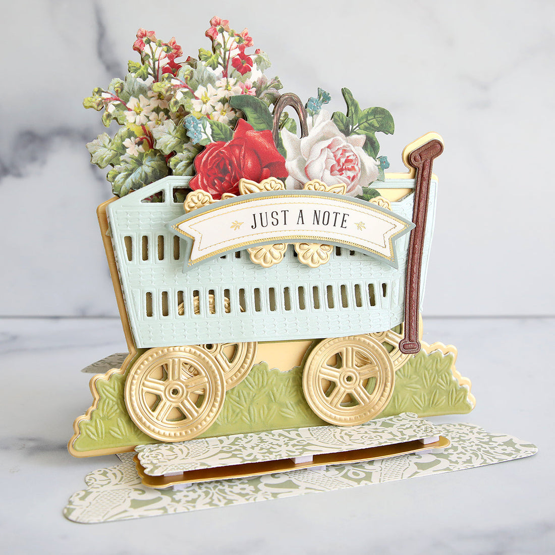Layered wagon card with flowers, green vellum, and gold accents.