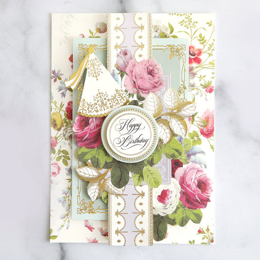 layered floral card with floral stickers, a collage card topper and party hat.