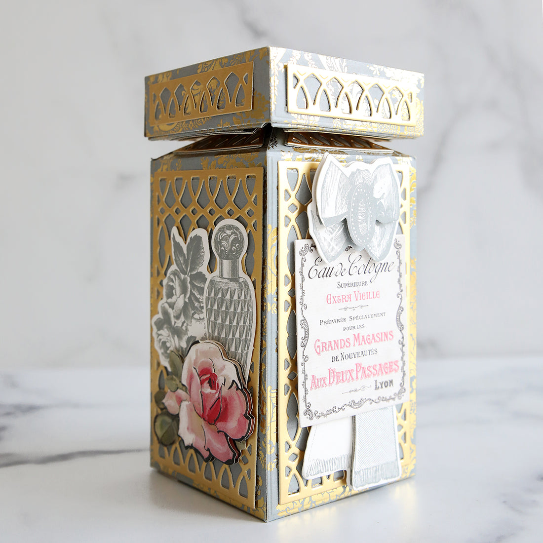 Gray and gold damask perfume box with gold foil details and perfume embellishments.