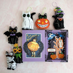 A collection of halloween ornaments and a book with a cat on it.