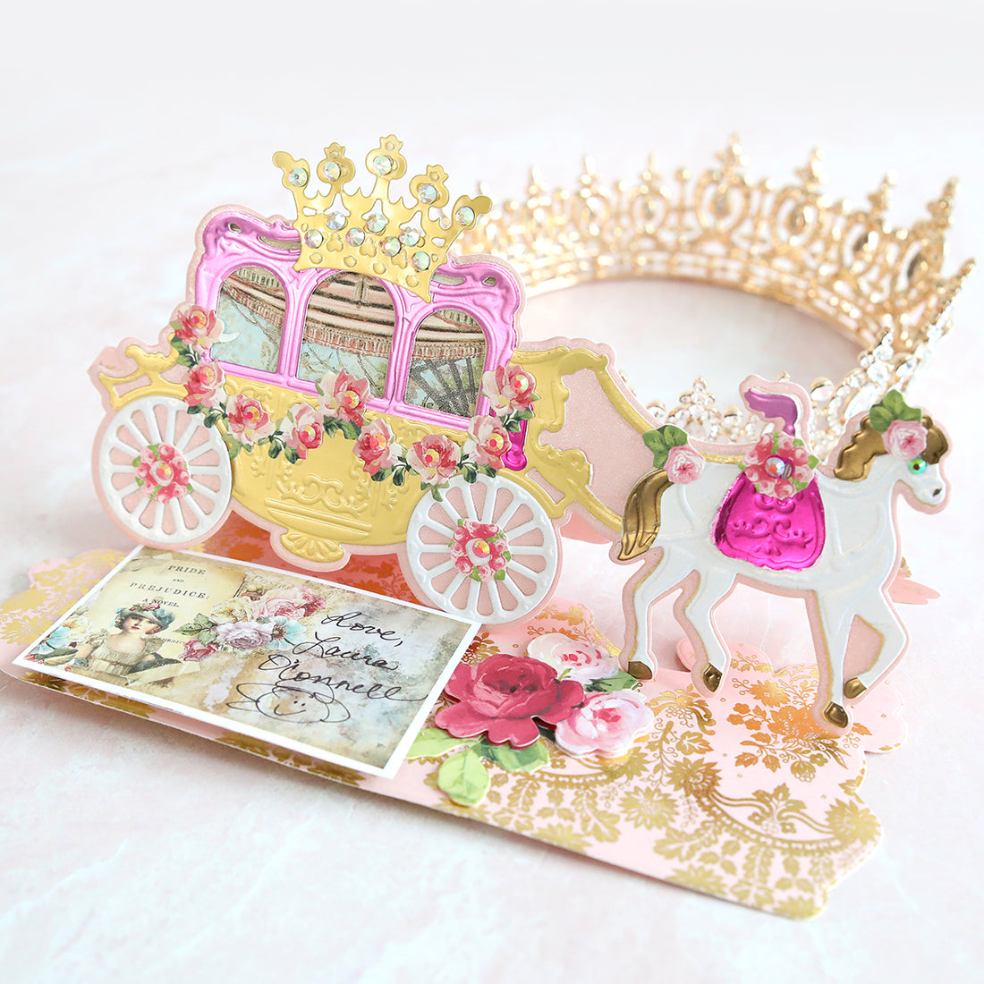 Pink, white and gold carriage card with a tiara in the background