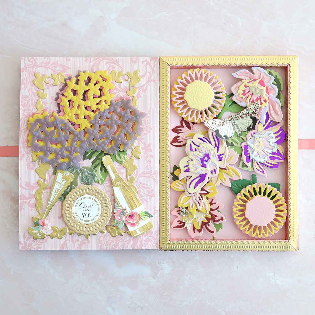 a pink and yellow card with flowers in a box.