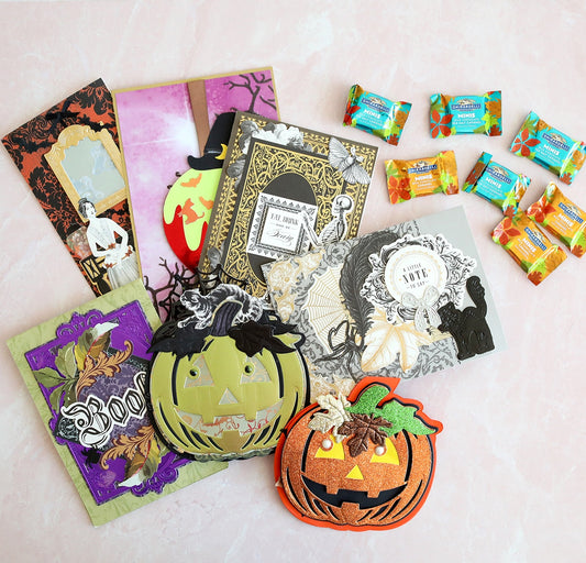 A variety of halloween cards and candy are laid out on a table.