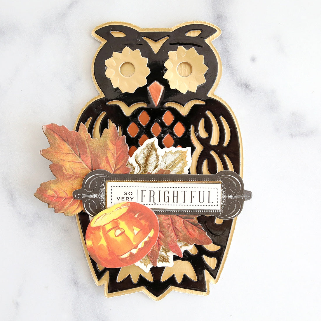 An owl with pumpkins and leaves on a marble table.