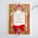 A christmas card with a red bow and ornaments.