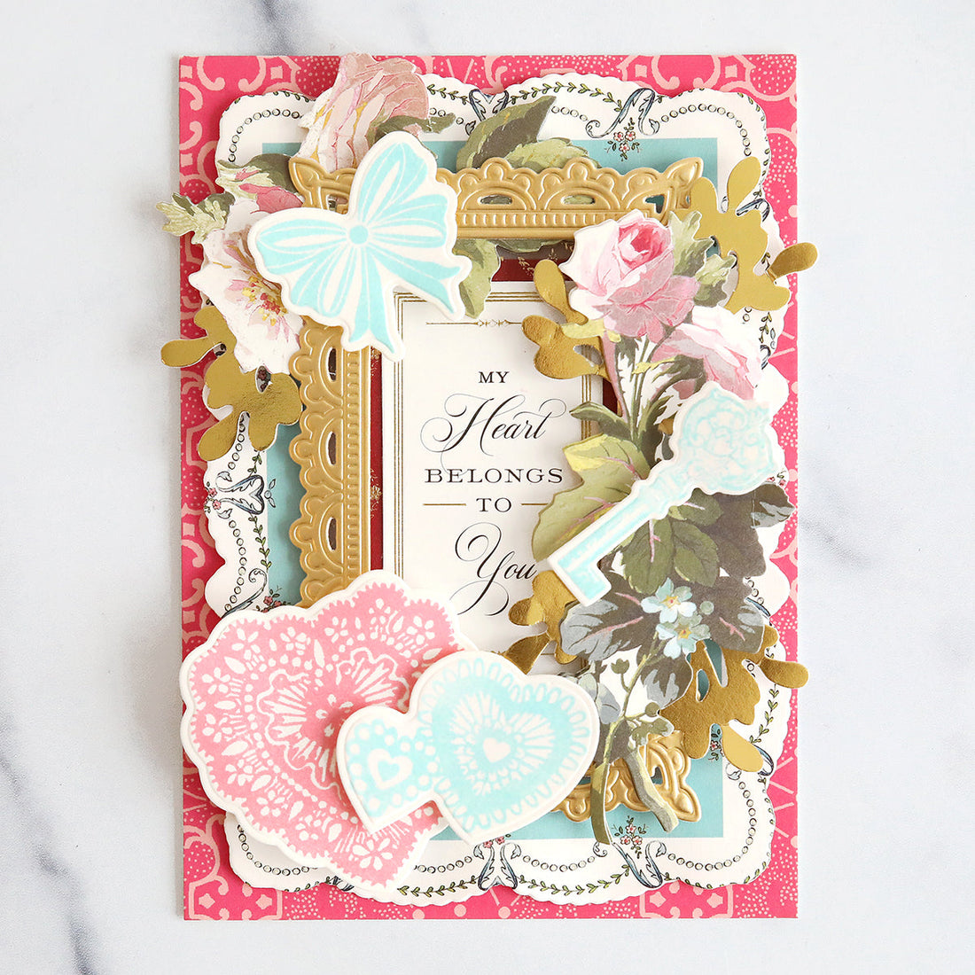 pink valentine with gold frame layer, floral embellishments and stamped diecuts in pink and blue