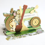 Gold, green and wildflower meadow tractor with shovel and rake.