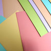 Various pastel-colored sheets of paper overlapped and arranged in a fanned-out pattern.