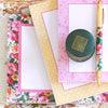 Three floral-patterned stationery sets with matching envelopes, a pen, and a round green ink jar are arranged on a white surface.