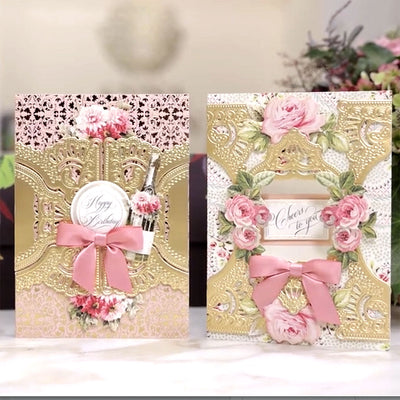 Two ornate greeting cards with intricate gold details and pink bows. The card on the left says "Happy Birthday" and the one on the right says "Cheers to you" adorned with floral designs.