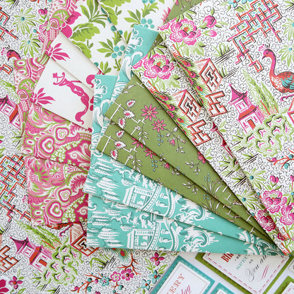 The Chinoiserie Papercrafting Kit with Dies includes assorted patterned sheets featuring botanical, animal, and geometric designs in pink, green, and blue—perfect for scrapbooking or handmade cardmaking projects.