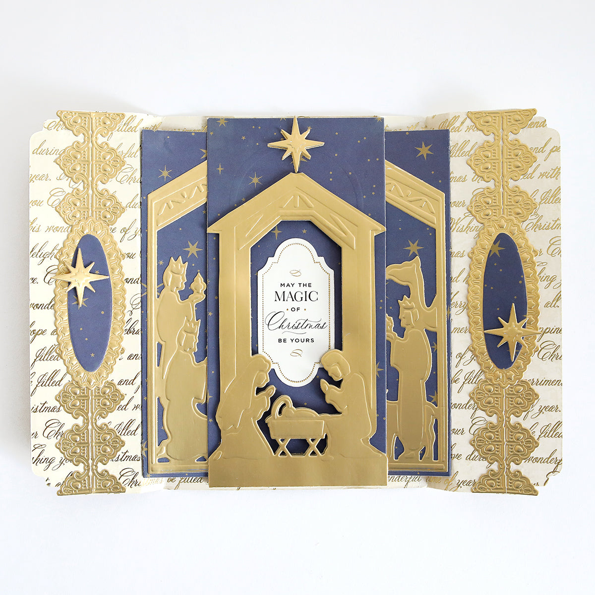 A folded Christmas card created with the Nativity Scenes Die Set Collection, featuring gold die-cut silhouettes and stars on a blue background with cream panels, reading “May the magic of Christmas be yours.”