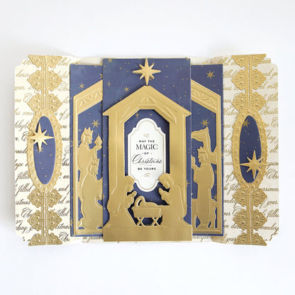 A folded Christmas card created with the Nativity Scenes Die Set Collection, featuring gold die-cut silhouettes and stars on a blue background with cream panels, reading “May the magic of Christmas be yours.”