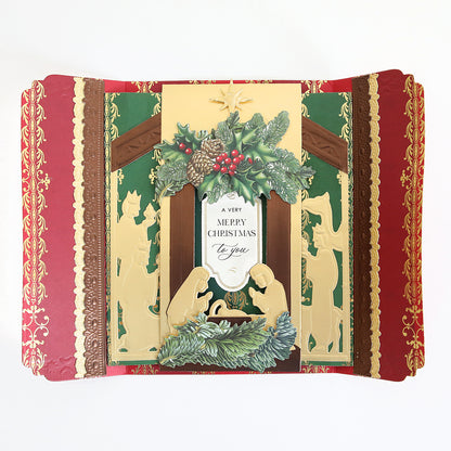 A gatefold Christmas card made with the Nativity Scenes Die Set Collection, featuring a nativity shadow box die-cut layered with holly and pinecones and text reading “A VERY MERRY CHRISTMAS to you.”