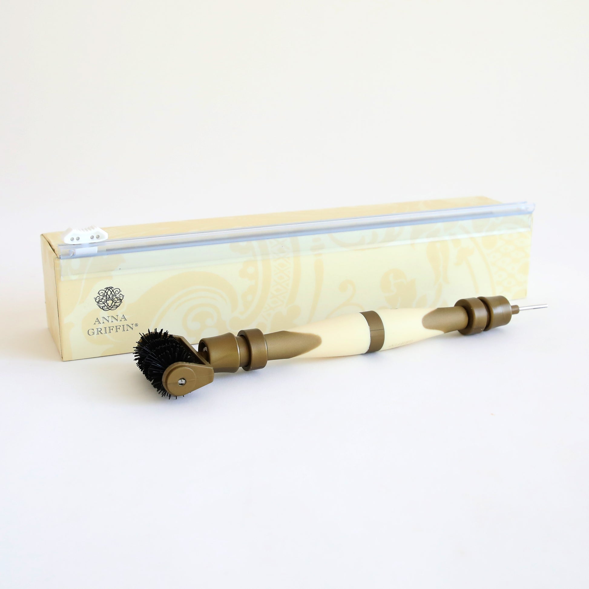 The Diecutting Essential Tools feature a versatile crafting tool with a beige handle and interchangeable ends, ideal for embossing and die-cutting, showcased in front of its branded packaging.