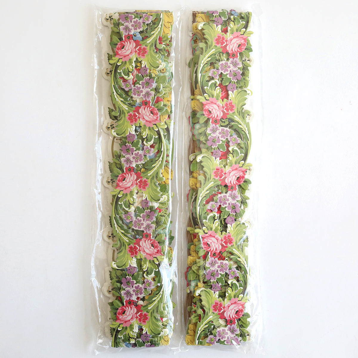 The Floral 12" Border Stickers, featuring intricately designed and vibrant floral patterns in pink, purple, green, and yellow, are perfect for adding charm to handmade cards or scrapbook pages. Each set of ribbons is conveniently packaged in clear plastic.