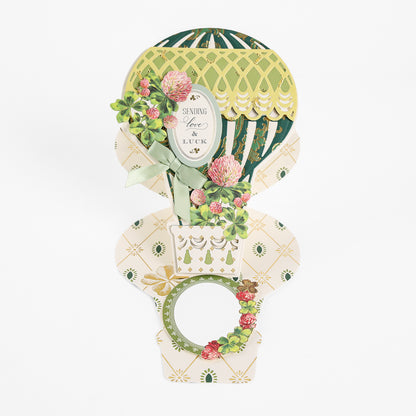 Crafted with the Hot Air Balloon Easel Die, this handmade pop-up greeting card showcases a hot air balloon adorned with elegant floral patterns. The pristine white background highlights the heartfelt message “Sending Love & Luck.”.