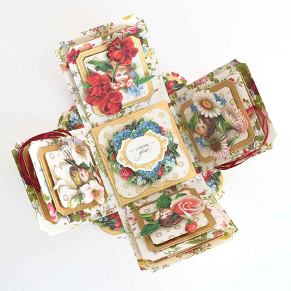 A floral-themed pop-up card made with Explosion House Dies and Materials, featuring vintage-style flower illustrations, die-cut embellishments, and a central "I adore you" message.