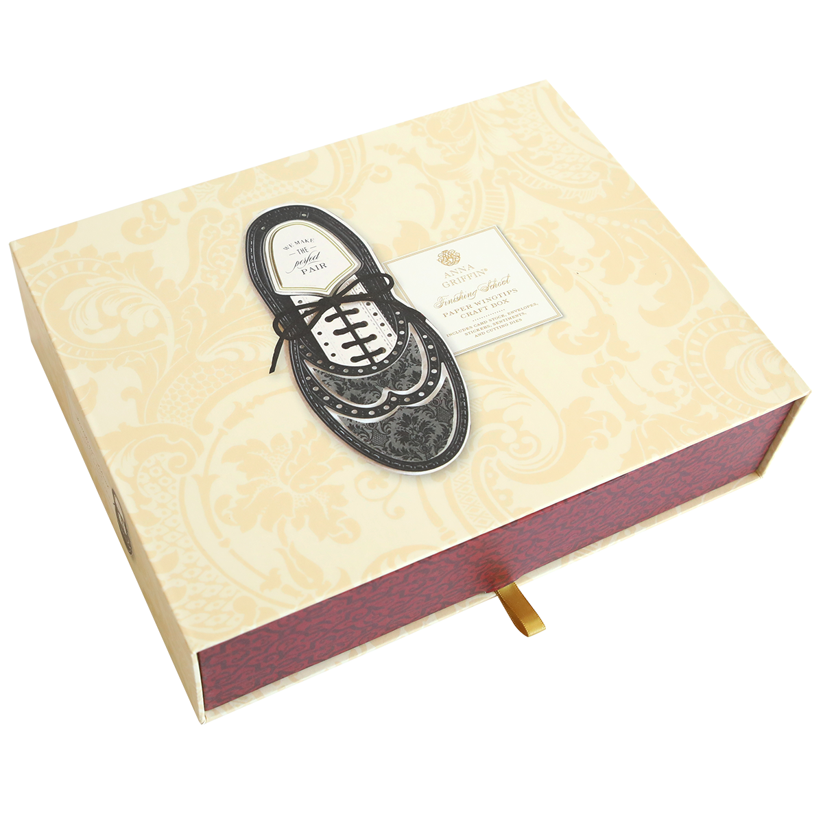 A Paper Wingtips Finishing School Craft Box with a black dress shoe illustration and a Paper Wingtips label on the lid. The box features a light yellow and white patterned design with a red side and a small handle at the bottom.