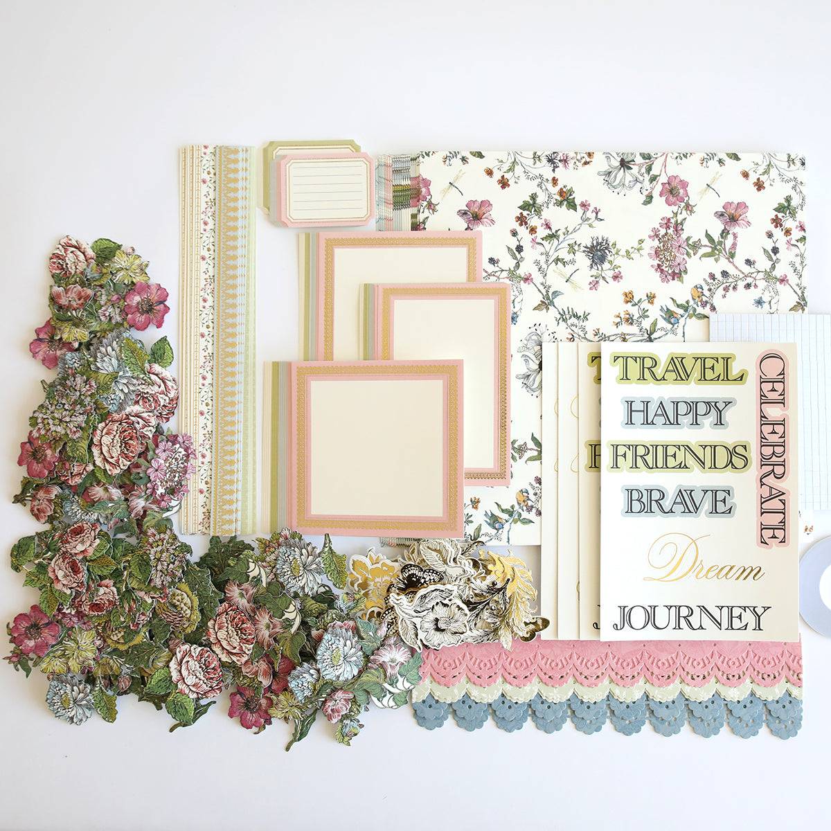 A flat lay image of various scrapbooking supplies, including floral patterned paper, decorative borders, cut-out flowers, word stickers, and blank cards with floral and pastel designs. Perfect for creating handmade cards or adding unique embellishments to your Wildflower Meadow Papercrafting Kit.