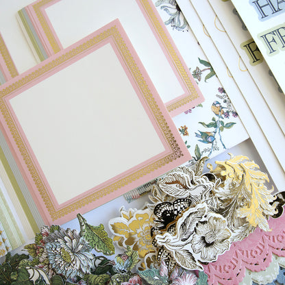 A collection of decorative stationery items including floral-patterned papers, empty cards with pink and gold borders, alphabet stickers, and an array of charming embellishments. Perfect for creating handmade cards or adding beauty to a Wildflower Meadow Papercrafting Kit.