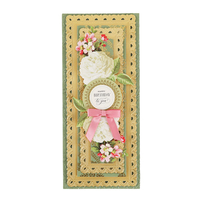 A decorative birthday card crafted from Toile Doublesided 300gsm Cardstock, featuring layered gold edges, white flowers, pink blossoms, green leaves, and a pink ribbon bow. The center reads “Happy Birthday to you.”.