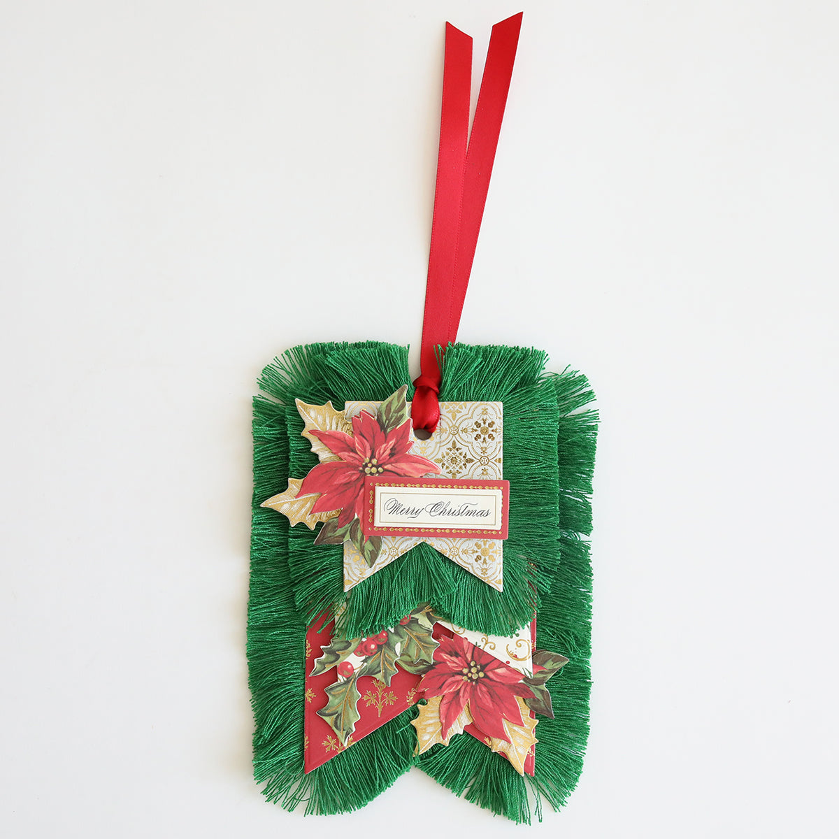 A green fringed Christmas Perfect Palette Fringe with red ribbon and a "Merry Christmas" tag, decorated with holly and poinsettia, featuring holiday-inspired colors.