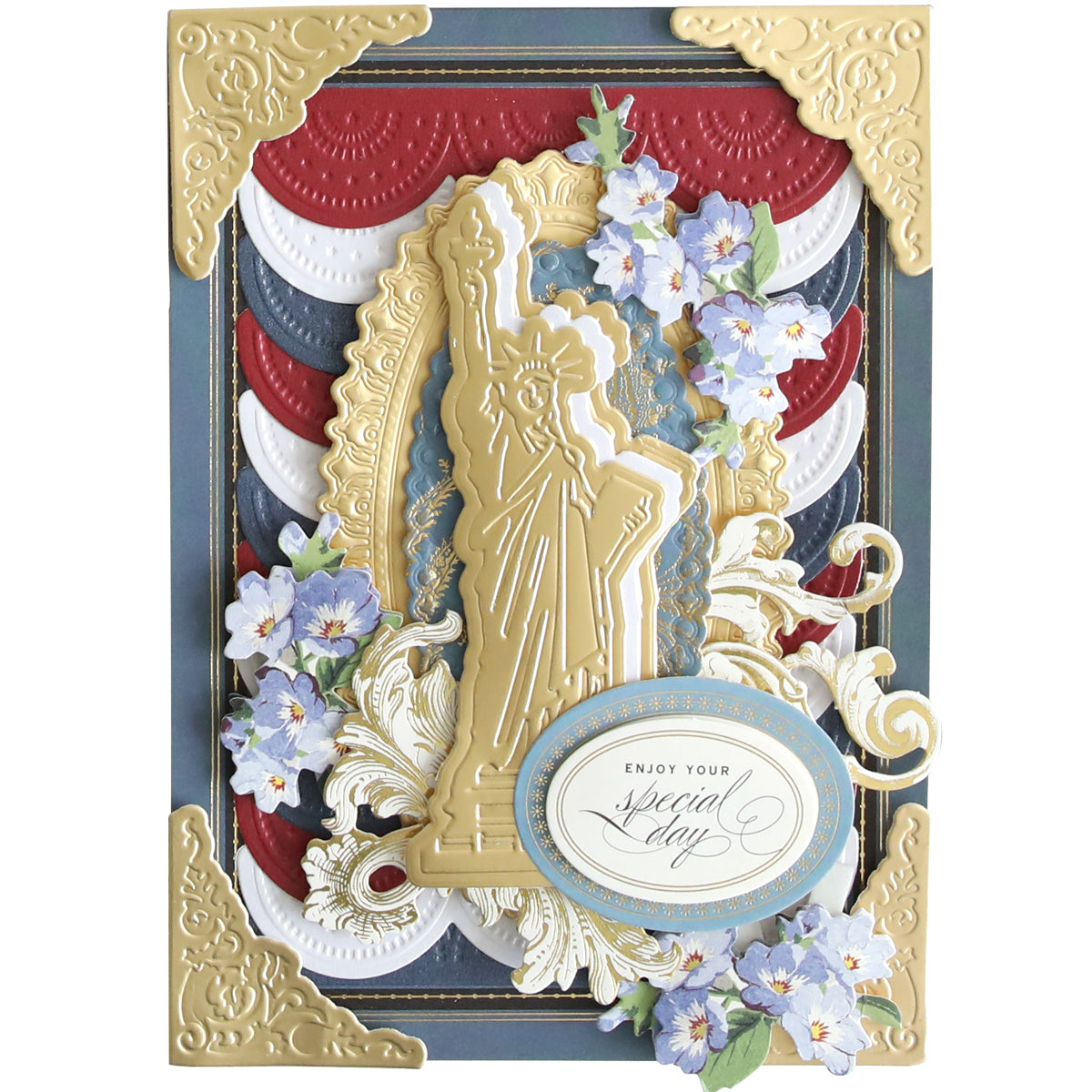 Introducing the Celebration Chest Craft Box Card Kit: a sophisticated greeting card featuring an exquisite gold Statue of Liberty with intricate patterns and blue flowers enhanced by foil embellishments. An oval label in the center beautifully declares, "Enjoy Your Special Day." This card is ideal for anyone who values star-studded designs and top-quality crafting materials.