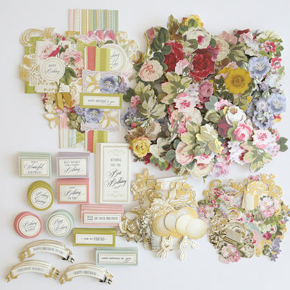 Assorted floral-themed craft supplies, including Birthday Greetings Refill Kit, paper cutouts, and ribbon cards, arranged on a flat surface—ideal for Card Toppers and Birthday Greetings Card Making Kits.