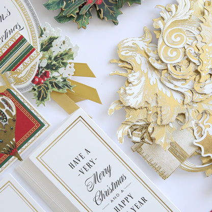 The Christmas Greetings Refill Kit includes an array of assorted Christmas cards adorned with intricate designs in gold and red, featuring holiday greetings, ribbons, holly, and ornaments. Ideal for creative projects, these exquisite embellishments can enhance your Christmas Greetings Card Making Kit.