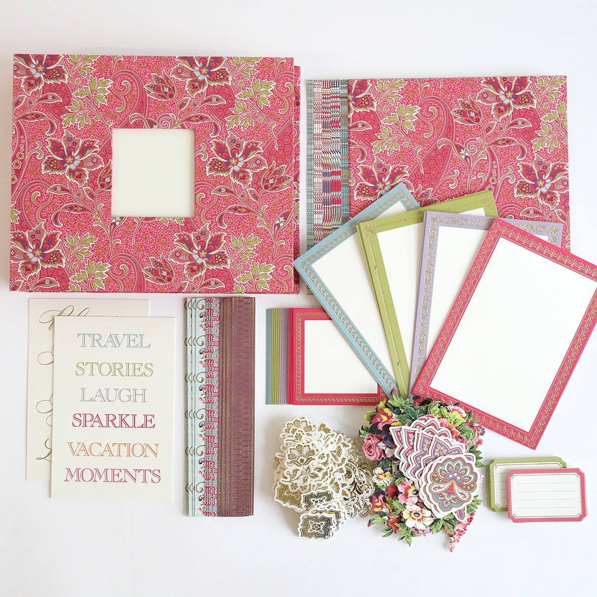 Scrapbooking supplies: the Simply Paisley Mini Album, a complete scrapbook kit featuring floral-patterned paper, colorful blank cards, scissors, stickers, and labels arranged neatly on a flat surface.