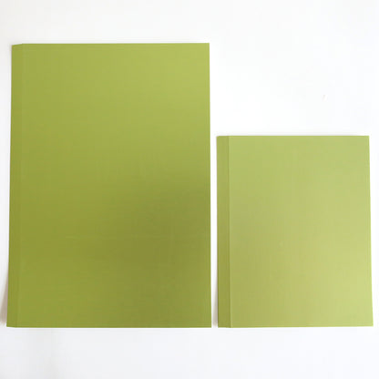 Two green books rest on a white surface; the larger one on the left, resembling Luxury Matte Foil Cardstock Green, stands next to the intricately detailed one on the right.