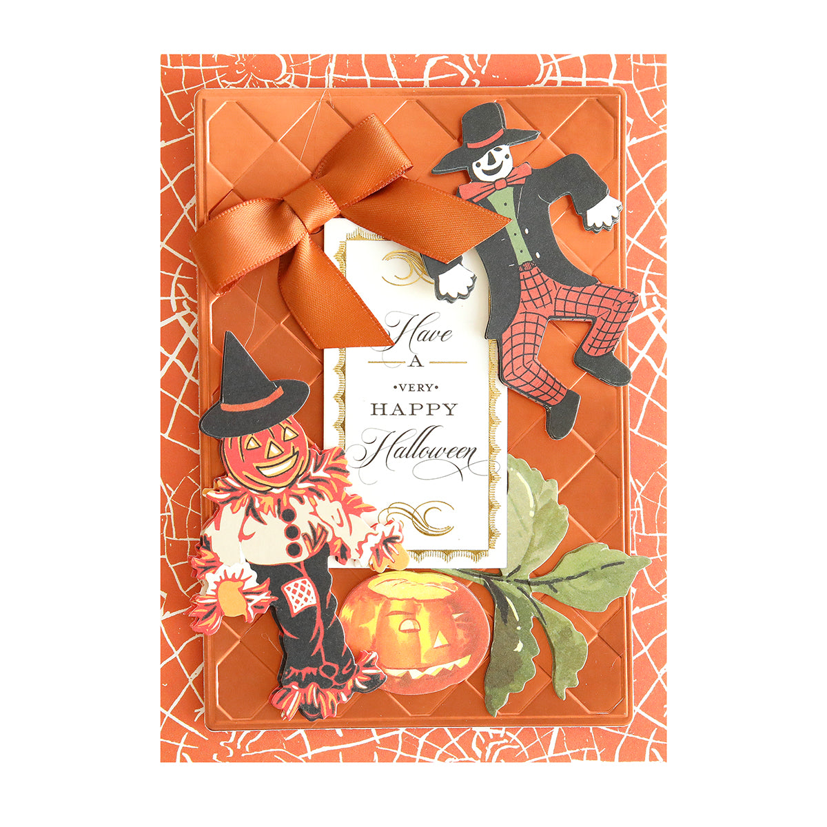 Handcrafted Halloween card, titled “Haunted Halloween Haul,” features an orange bow, a spiderweb background, a pumpkin, fall leaves, and two scarecrow figures—including one in a witch hat—all made with premium Halloween craft supplies. Festive glitter cardstock adds extra sparkle, while cheerful Halloween stickers finish the design. Center text reads: “Have a very Happy Halloween.”.