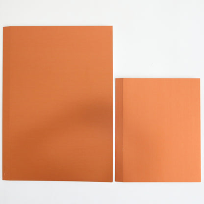 Two closed orange books are placed side by side on a white surface; the book on the left is larger than the one on the right, resembling stacked sheets from the Fall Matte Foil Cardstock Bundle—perfect for your next creative project.