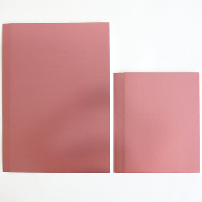 Two stacks of Luxury Matte Foil Cardstock Pink are placed side by side on a white surface; one stack is larger and one is smaller—ideal for diecutting projects.